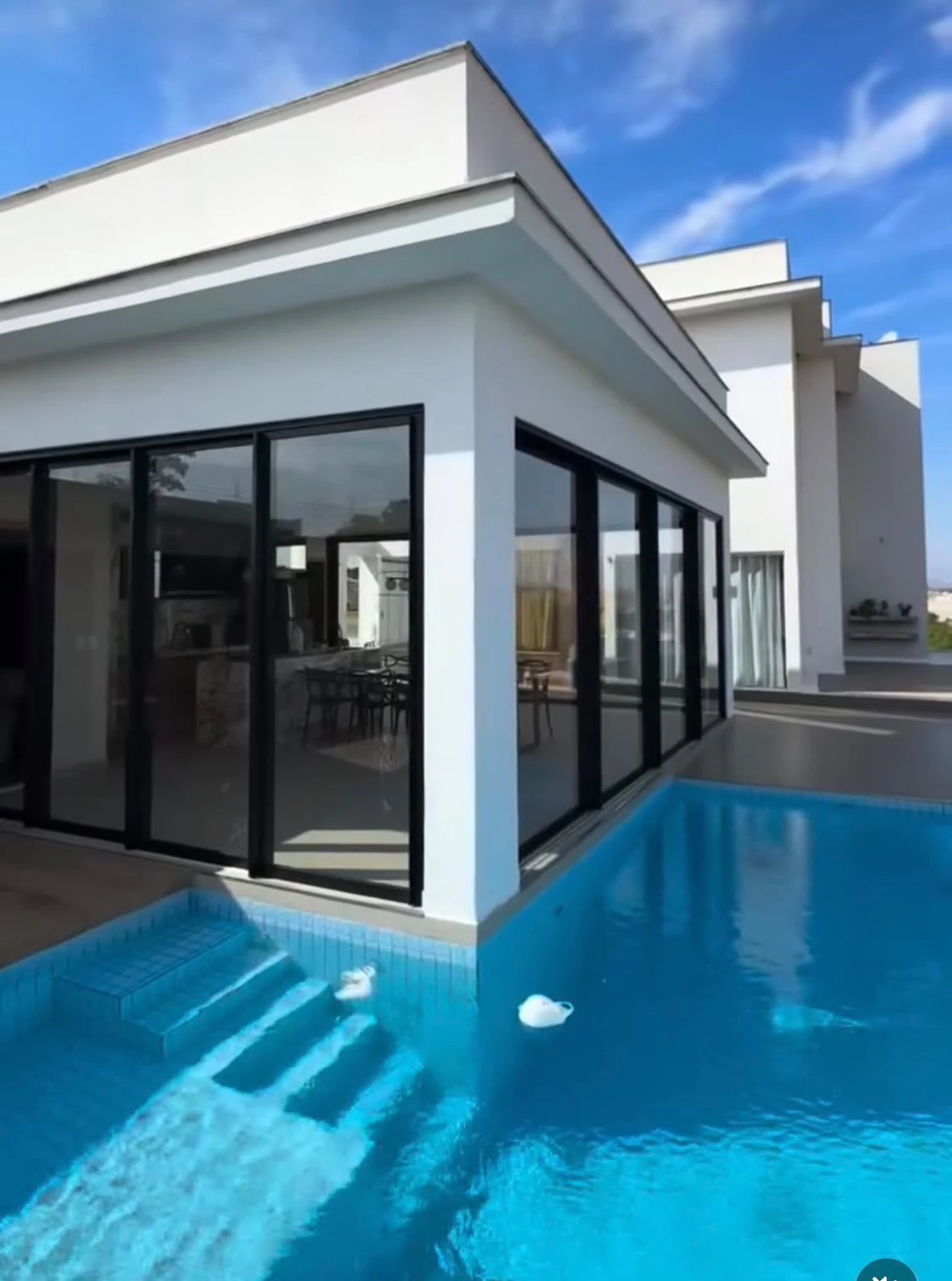 Residência contemporânea com piscina e amplas esquadrias pretas de vidro