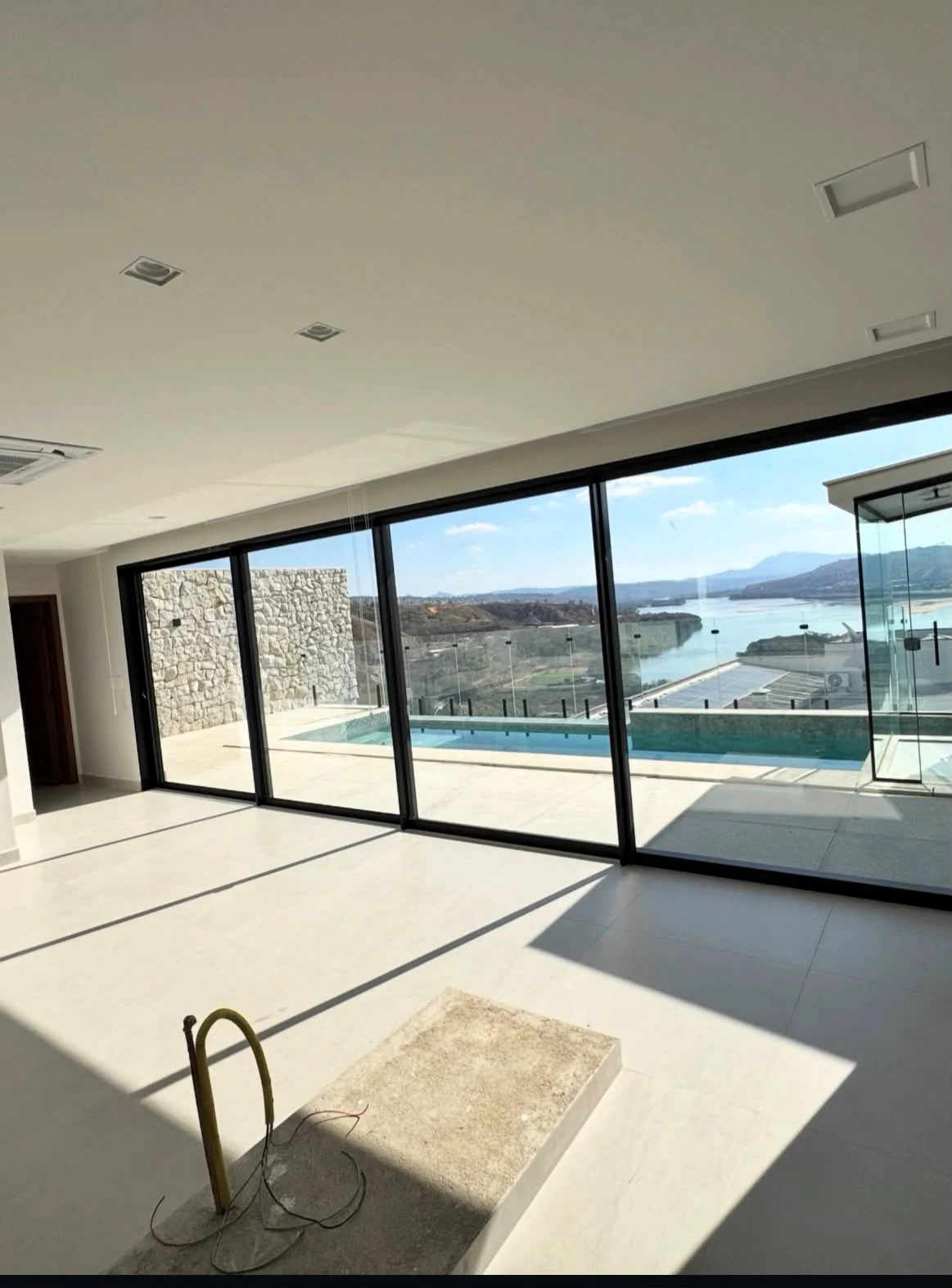 Ambiente integrado com grandes esquadrias pretas de correr, varanda e vista para a piscina